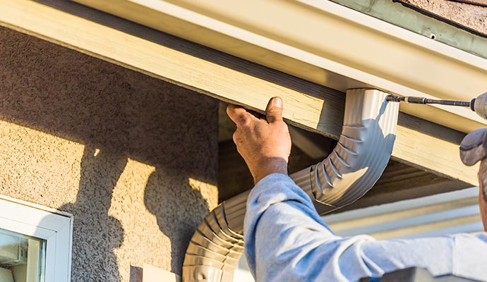 A person installing gutter at house