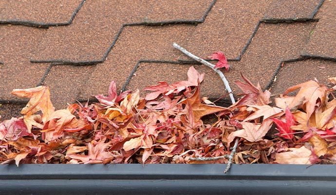 Clogged gutter filled with dry leaves, sticks and built-up debris