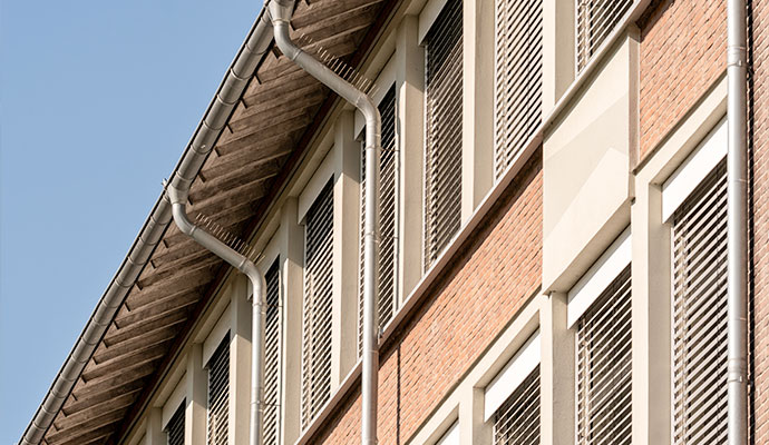 Multi-story commercial brick building with clean gutters and downspouts