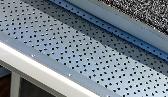 Perforated metal gutter guard installed on a roof gutter