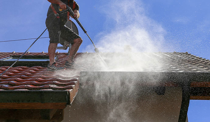 Professional technician flushing roof gutters