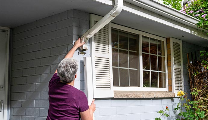 Technician inspecting and servicing a residential downspout