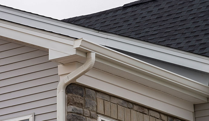 White gutter and downspout installed along residential roofline
