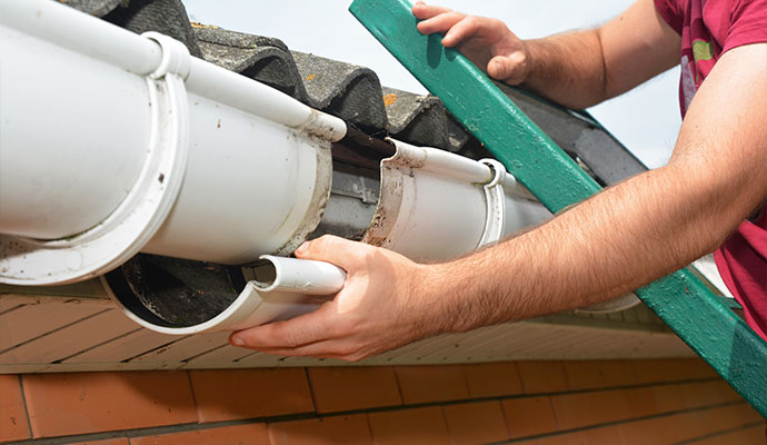 Man repairing broken roof gutter