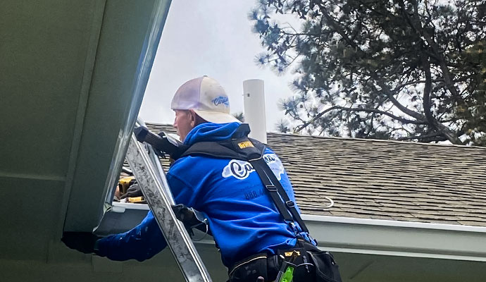 Worker installing gutters on roof