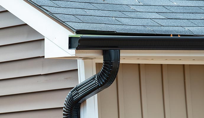 A newly installed aluminum gutter and downspout system attached to a home roofline for effective rainwater drainage.