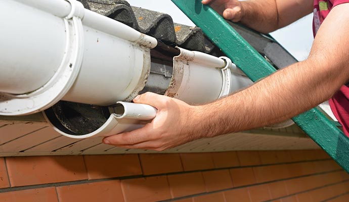 A professional repairing a damaged gutter section to restore proper water flow and prevent further issues.