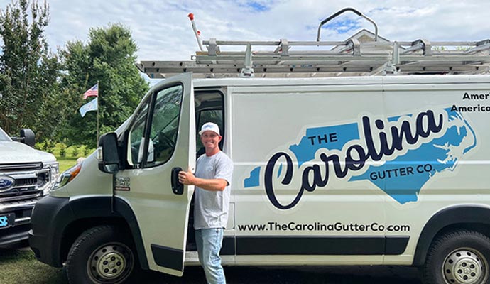 A professional gutter company technician standing beside a branded service van, representing reliable family-owned gutter services.