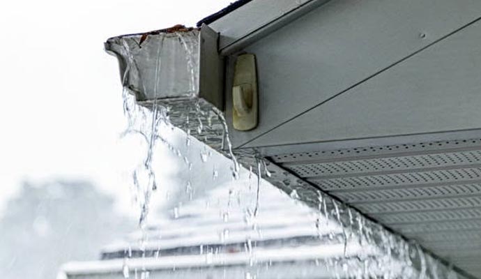 Rainwater overflowing from a clogged roof gutter