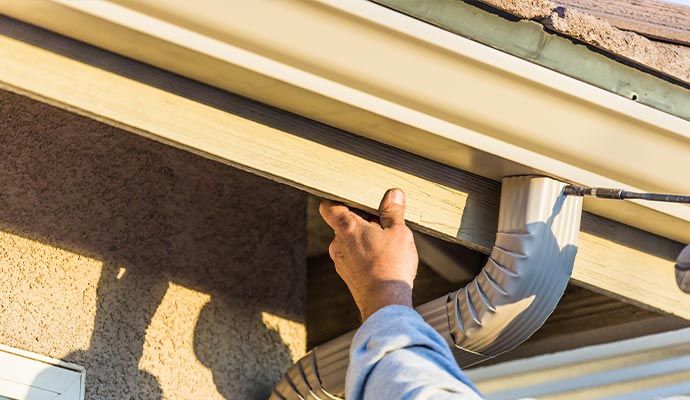 Person repairing gutter with equipment