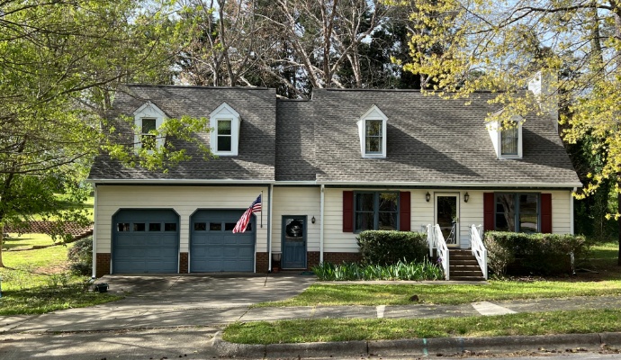 A two-story cream-colored house with newly replaced gutter in Raleigh, NC
