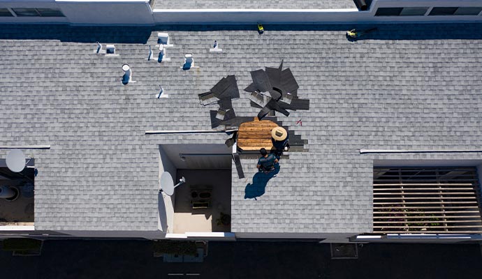 An overhead view of roofing professionals working on a commercial building roof during repair or replacement.